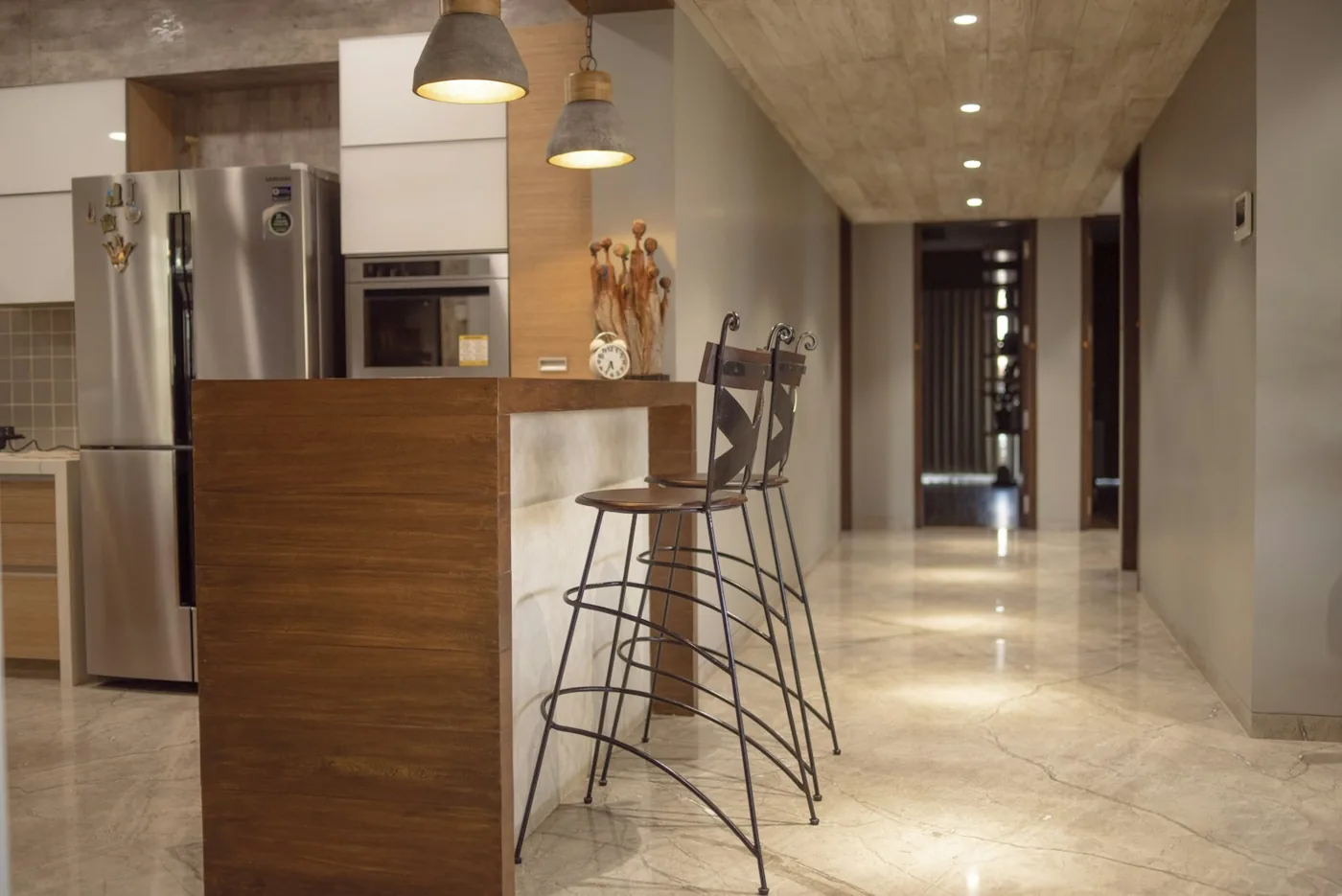 Kitchen with breakfast counter, tall fridge, built-in oven and pendant lights